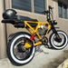 Beast Electric Bike in Colour Spicy Mustard with White-Walled Tires and a Black Helmet Mounted on the Rear Rack