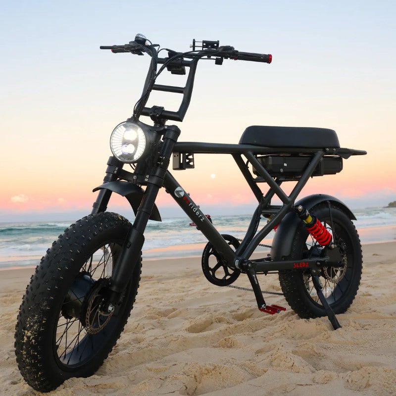 Sledz 2.0 Beast Ebike in Colour Grey Wolf Parked on a Sandy Beach at Sunset